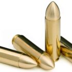 Close-up of 12.7x42mm 280gr solid brass spire point cartridges arranged on white background—deep-penetrating monolithic ammo for hunting and tactical use.