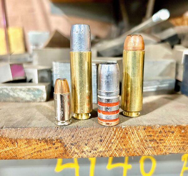 Two rounds of 50 Beowulf ammunition next to 9mm Luger round and 700gr lead bullet