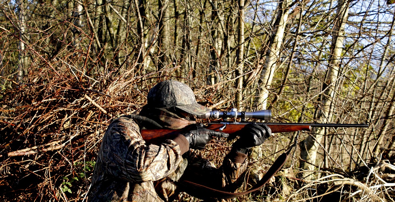 man-holding-a-rifle-standing-in-a-natural-setting