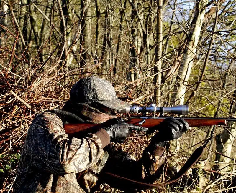 man holding a rifle standing in a natural setting