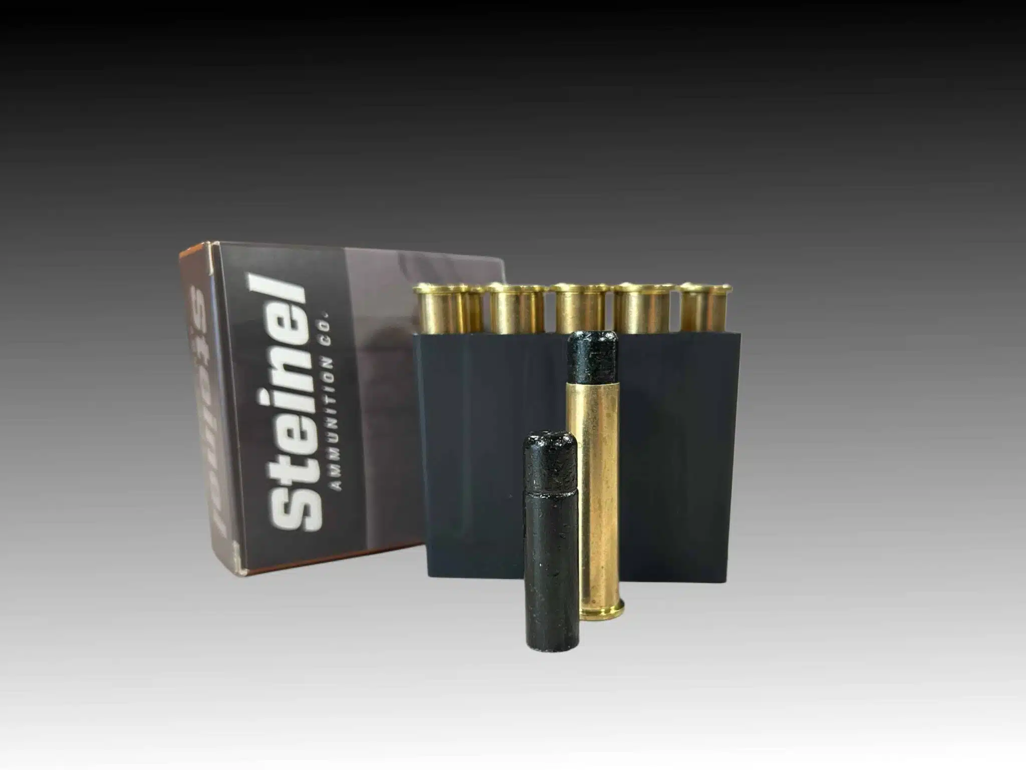 Close-up of Steinel Ammunition's 45-70 Government Subsonic 777gr 'Lucky Ram' rounds, featuring a prominent coated lead bullet and brass cartridge in the foreground, with packaging and additional rounds in a black holder in the background.