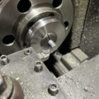 Machining 777gr Lucky Ram bullet prototype—turned on lathe using collet chuck, showing precision nose profiling in progress