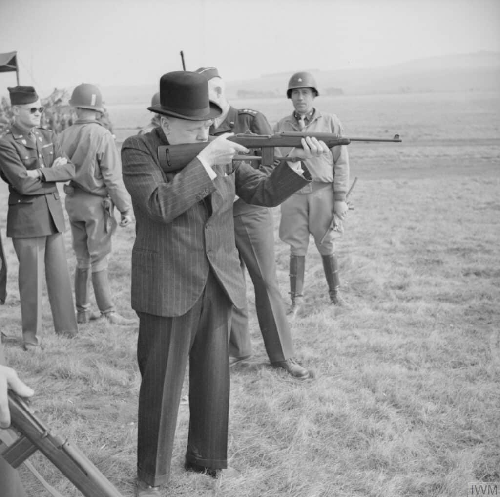 Winston Churchill fires an American M1 carbine during a visit to the U.S. 2nd Armored Division on Salisbury Plain, 23 March 1944.